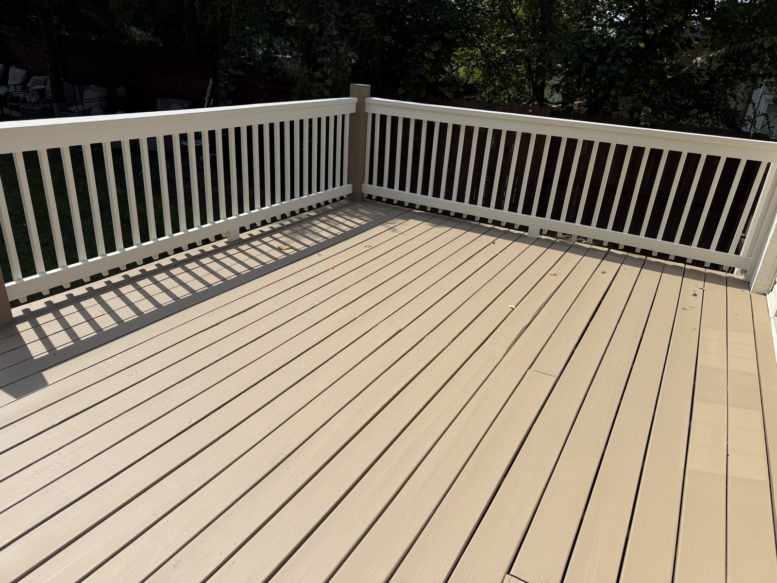 Corner of a tan deck with white painted balusters — deck restoration by Roca’s Painters of Mebane, NC