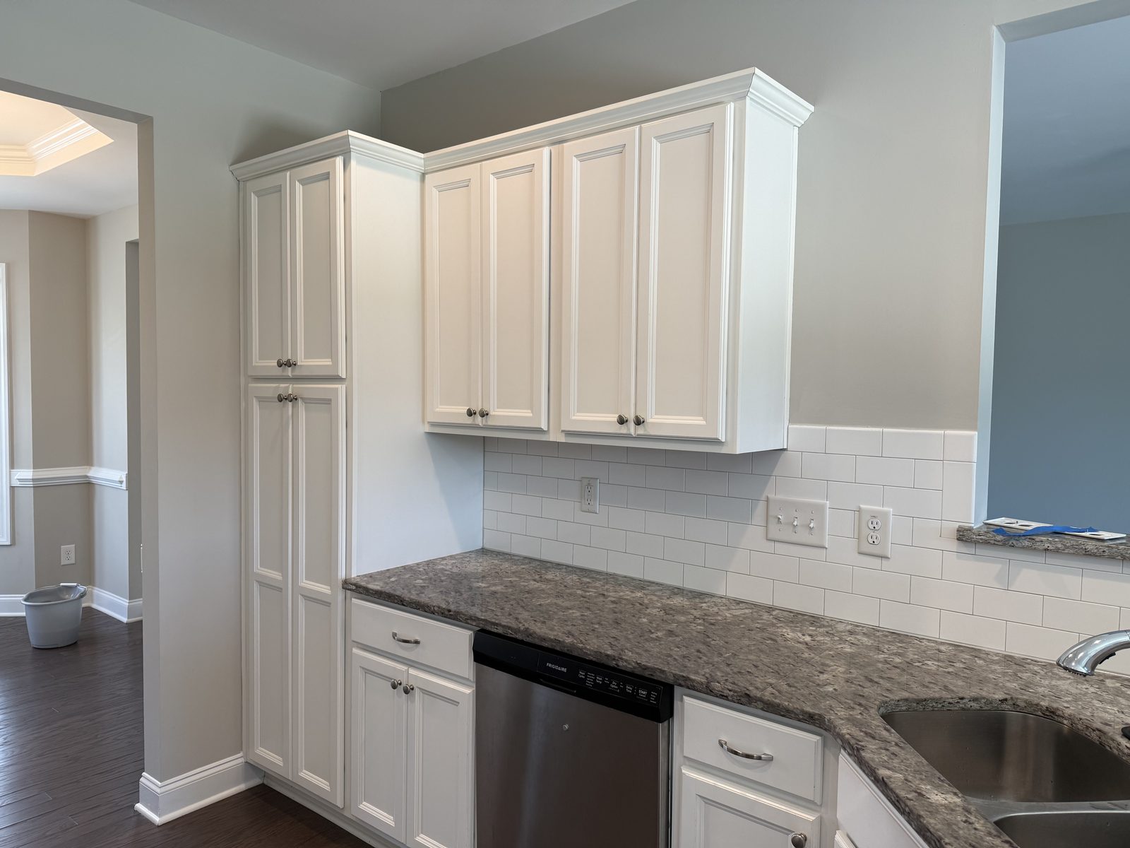 Upper cabinets and pantry column refinished in a satin white over raised-panel doors — cabinet painting by Roca’s Painters of Mebane, NC