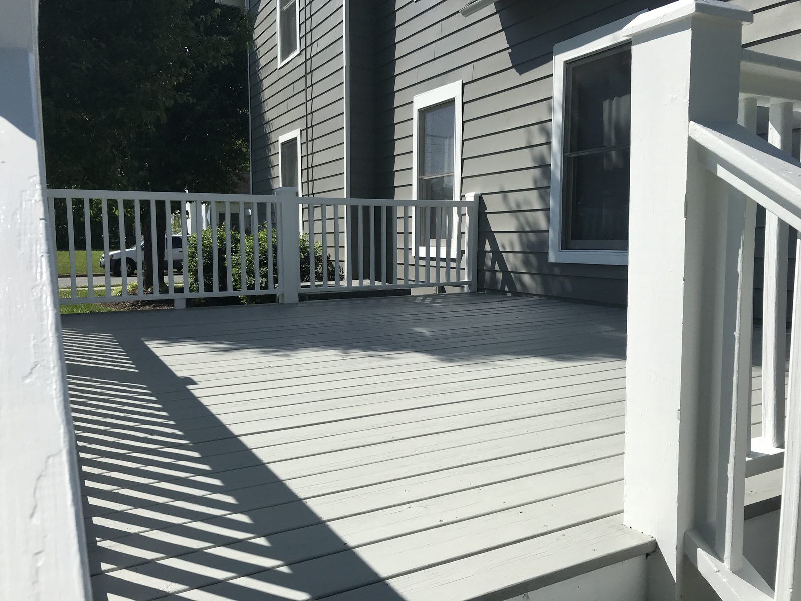 Deck floor painted gray next to gray siding — deck restoration by Roca’s Painters of Mebane, NC