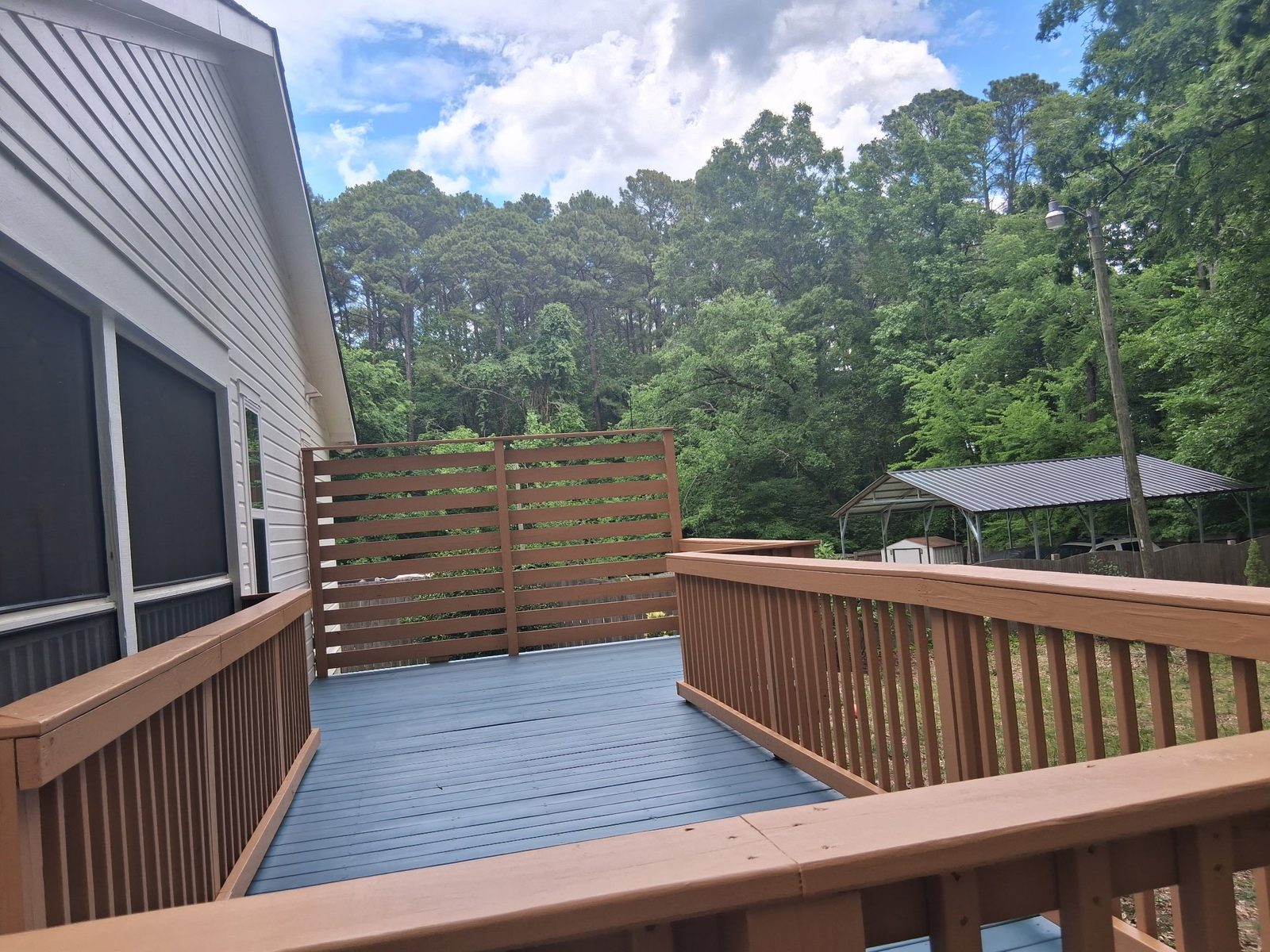Deck with gray painted floor and tan railings with a privacy screen — deck restoration by Roca’s Painters of Mebane, NC