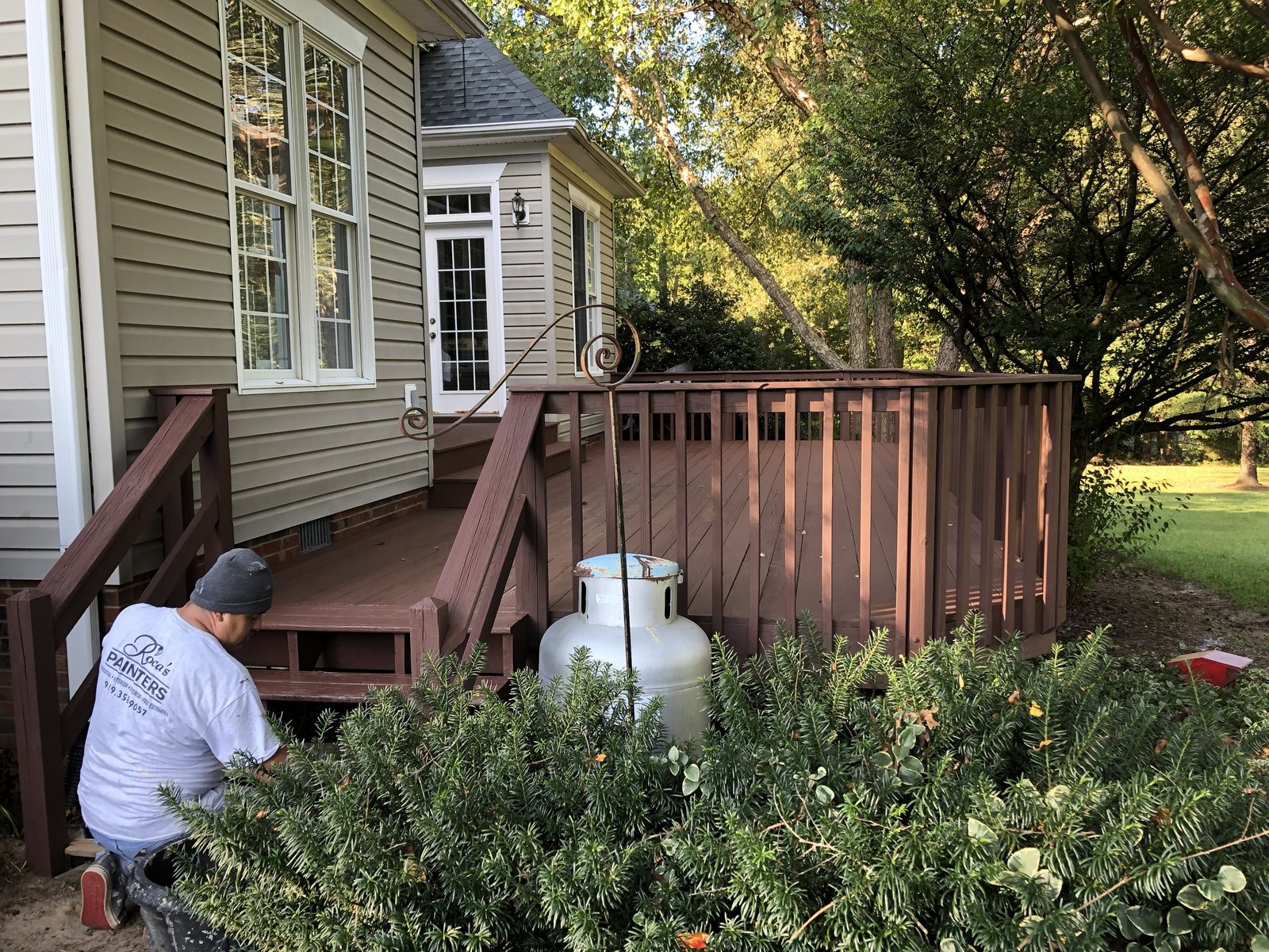 Painter applying stain to a backyard deck — deck restoration by Roca’s Painters of Mebane, NC