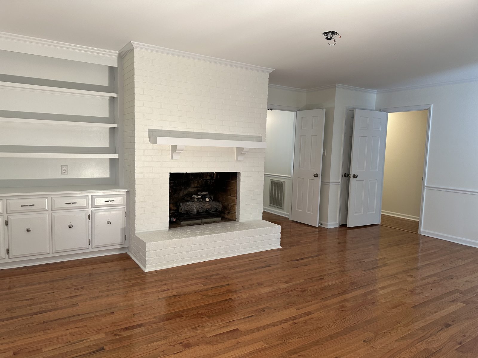 Painted white brick fireplace with built-in shelves and cabinets — interior painting by Roca’s Painters of Mebane, NC