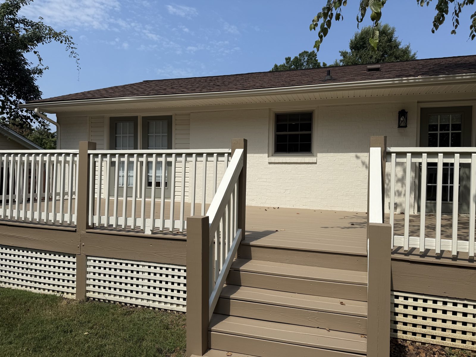 Tan deck with white railings and lattice skirting — deck restoration by Roca’s Painters of Mebane, NC