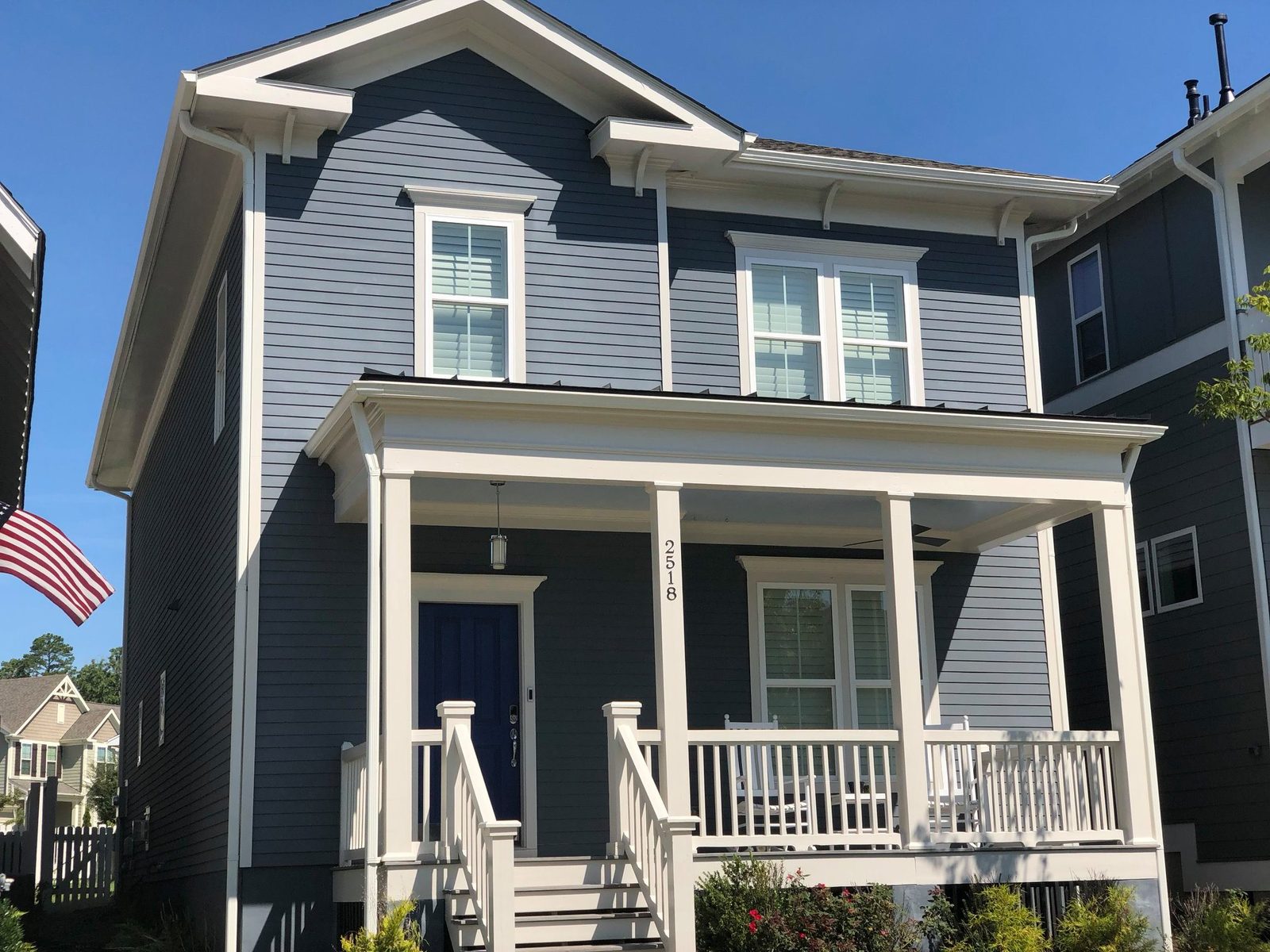 Navy two-story home with white trim and covered front porch painted — exterior painting by Roca’s Painters of Mebane, NC