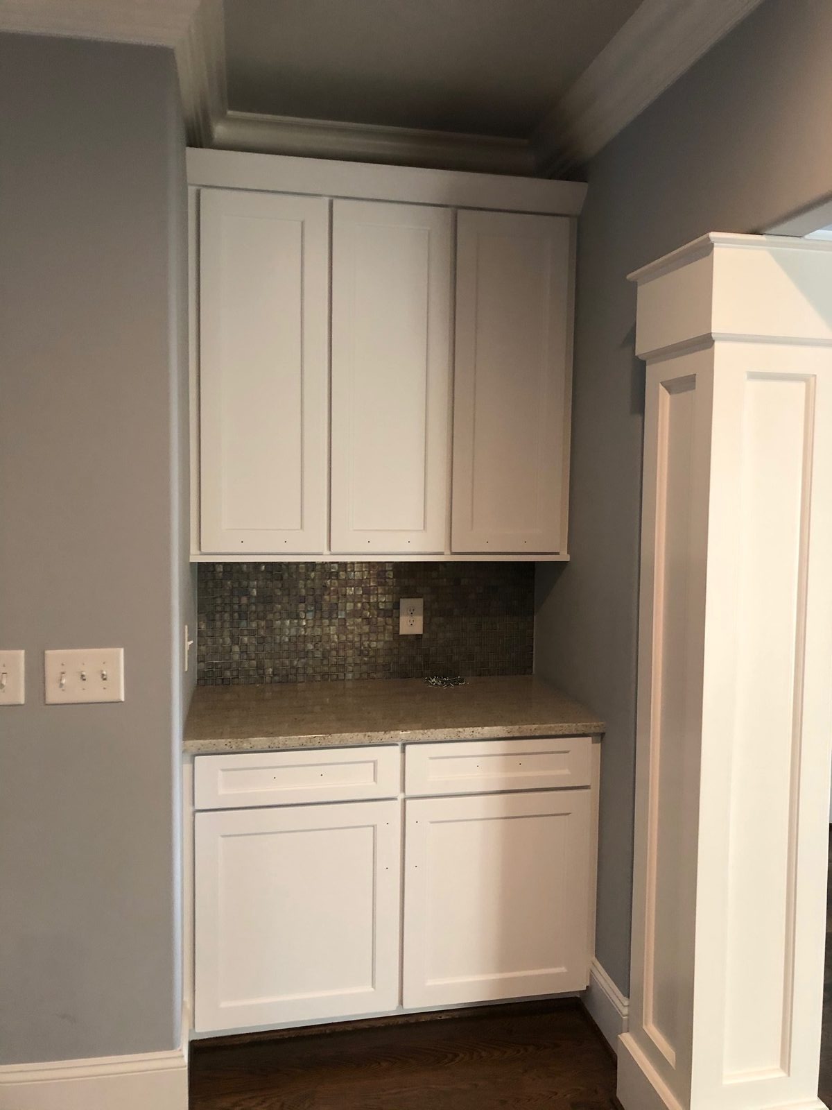 Butler's pantry cabinets painted white against a glass mosaic backsplash — cabinet painting by Roca’s Painters of Mebane, NC