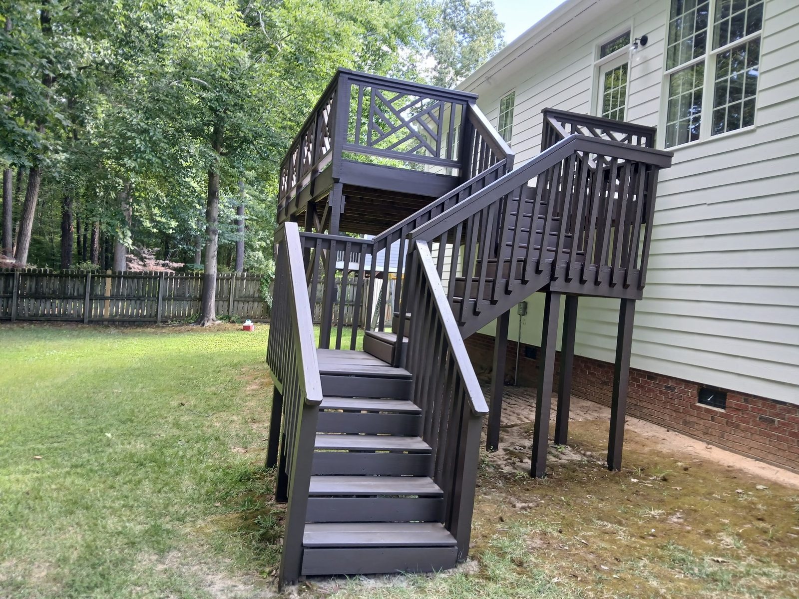 Deck stairs and railings stained dark against white siding — deck restoration by Roca’s Painters of Mebane, NC
